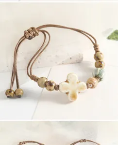 Handmade ceramic bead bracelet with adjustable woven cord and cute cross pendant detail.