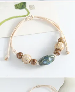 Detailed shot of handmade ceramic bead bracelet with woven cord, featuring rustic blue glaze bead.
