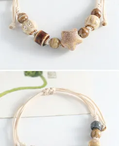 Close-up detail shot of handmade ceramic beads and braided cord bracelet with star charm.