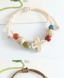 Close-up detail of handmade ceramic bead bracelet with colorful glazed clover charms.