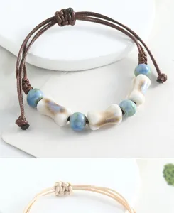 Detail shot of handmade ceramic bead bracelet with braided cord, showcasing delicate craftsmanship.