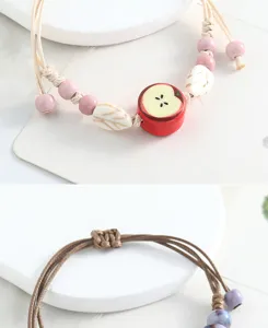 Handmade ceramic apple bracelet with woven cord, cute fruit charm jewelry for women.