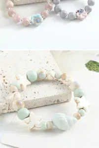 Vista dettagliata del bracciale di perle in ceramica con ciondoli stella, design elegante.