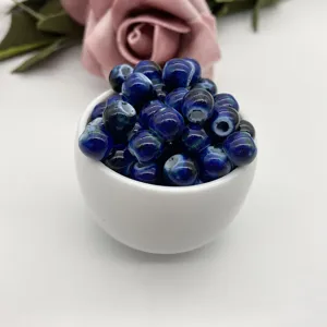 Close up of deep blue glazed ceramic loose beads in a white bowl for DIY jewelry making.