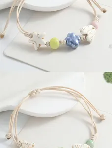 Charming ceramic beaded bracelet with cute star and butterfly charms, braided cord design detail.