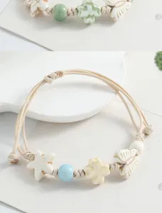 Ceramic beaded braided bracelet detail view, cute star butterfly and clover charms.