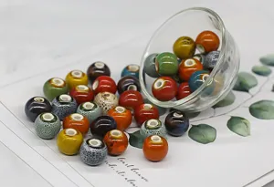 Detailed shot of colorful glazed ceramic beads in a glass bowl, perfect for DIY jewelry making.