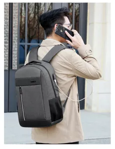 Detail shot of business laptop backpack with USB charging port worn by model outdoors.