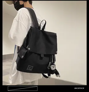 Casual black canvas backpack for students, stylish minimalist flap design with cute monkey charm.