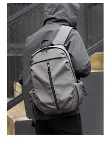 Detail shot of a minimalist grey backpack worn outdoors, showcasing its sleek design.