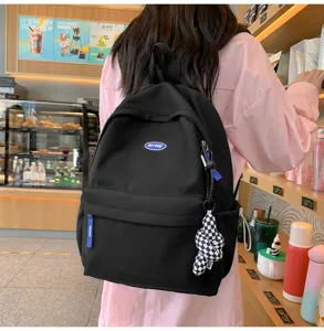 Detailansicht des schwarzen Freizeitrucksacks mit Fronttasche und kariertem Anhänger.