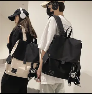 Casual canvas school backpack for men and women, minimalist flap daypack with cute monkey charm.