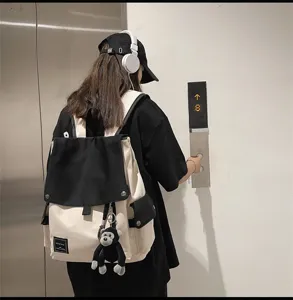 Casual canvas backpack for students, stylish colorblock design with cute monkey charm.