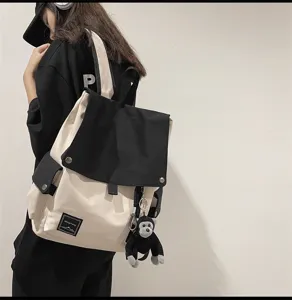 Detail view of a stylish black and white canvas backpack worn by a model, featuring flap and pockets.