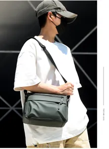 Close-up detail of the dark green waterproof messenger bag with dual zippers and spacious capacity.