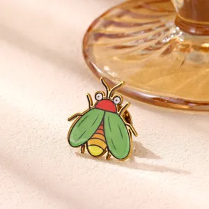 Close-up detail shot of a cute cartoon bug enamel pin featuring vibrant green wings and a red head.