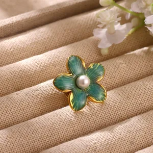 Close-up detail of the elegant blue-green enameled flower brooch with a central pearl.