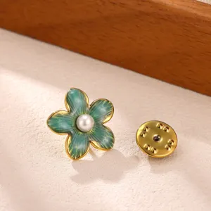 Detailed shot of an enamel flower brooch with a central pearl and gold trim. Perfect accessory.