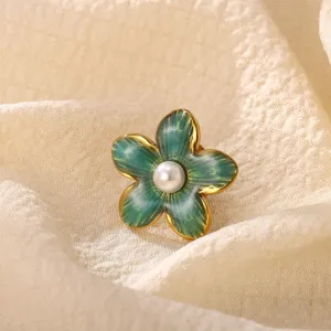 Exquisite detail view of the green enamel flower brooch with a central pearl and gold finish.