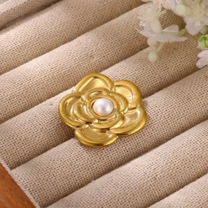 Detailed shot of golden camellia flower brooch with pearl center on display tray.