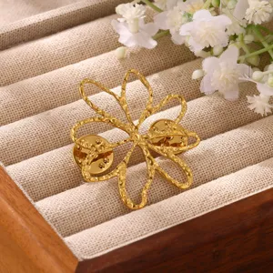 Detail view of the elegant gold-plated openwork flower brooch pin resting on a jewelry tray.