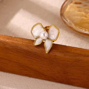 Close-up detail shot of the stainless steel pearl bow brooch, showing exquisite texture and craft.