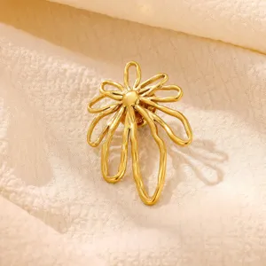 Close-up detail shot of a golden abstract flower metal brooch, elegant accessory design.
