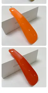 Orange plastic shoe horn with hanging hole portable convenient tool for daily home use footwear.