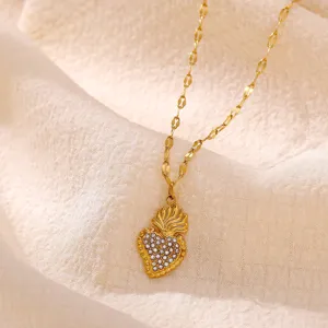 Nahaufnahme einer goldenen Herz-Anhänger-Halskette mit funkelnden Kristallen auf Stoff.