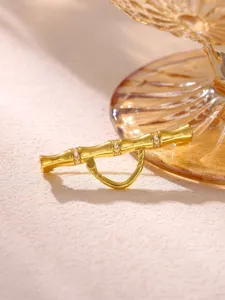 Gros plan détaillé du pendentif broche nœud de bambou doré avec pavé de zirconias scintillants.