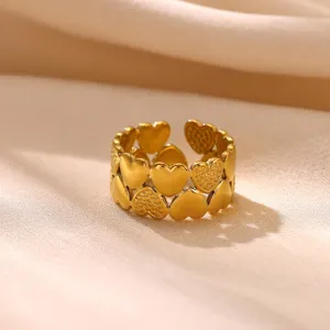 Detailopname van de gouden ring met afwisselende hartpatronen en een brede pasvorm.