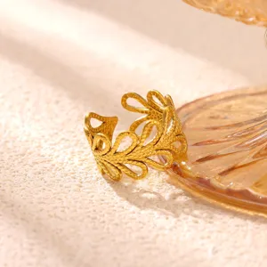 Gedetailleerde close-up van een brede gouden roestvrijstalen open ring met hol hartbladpatroon.