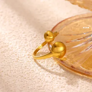 Detailweergave van een stijlvolle minimalistische gouden open ring met dubbele sferen.