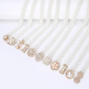 Close-up detail of elegant pearl waist chains featuring various rhinestone metal buckles.