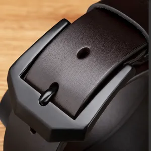 Men's leather belt detail close-up showing dark strap and matte black metal buckle.