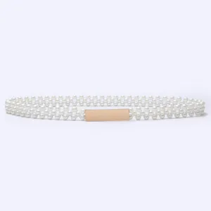 Close-up detail of a multi-row pearl waist belt featuring a shiny gold rectangular metal buckle.