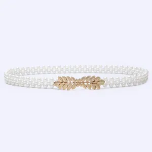 Detail view of a sweet elastic pearl waist belt with a gold leaf buckle for dresses.