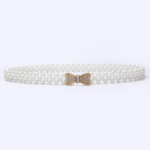 Detailed shot of a gorgeous women pearl waist belt with a sparkling rhinestone bow buckle.