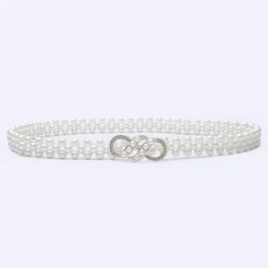 Close-up detail of a white pearl elastic waist belt with a sparkly rhinestone buckle.