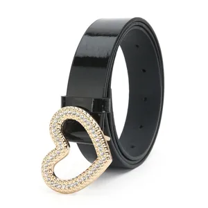 Gros plan sur la ceinture en cuir vernis noir avec boucle cœur strassée scintillante.