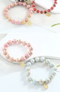 Gros plan détaillé de bracelets de perles en céramique colorée avec charms dorés de bijoux.