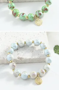 Vue détaillée du bracelet en perles de céramique, perles vernies brillantes avec entretoises dorées.