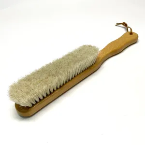Brosse de nettoyage en bois à long manche avec poils souples et lanière en cuir.