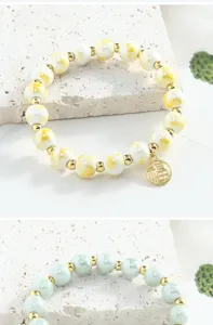 Vue détaillée du bracelet de perles en céramique émaillée avec des intercalaires dorés et un charme.