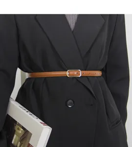 Detailed view of women's thin brown leather belt with metal buckle styled on a black blazer.