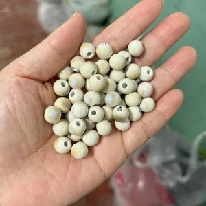 Detailed close-up of smooth round ceramic beads, natural beige DIY jewelry materials.