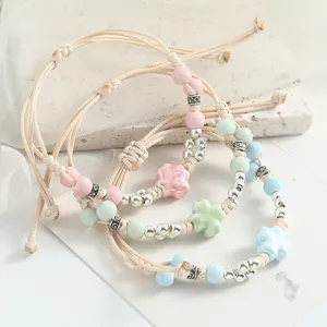 Handmade ceramic flower beaded bracelet close-up, adjustable braided cord jewelry.