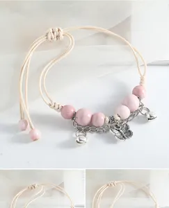 Gros plan sur le bracelet de perles en céramique rose avec breloque papillon.