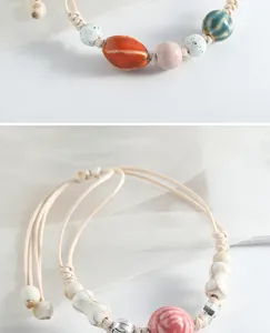 Vue de détail de bracelet de perles en céramique fait main, cordon tissé vintage.