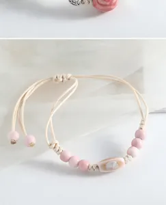 Bracelet de perles en céramique rose fait main, détails délicats et cordon ajustable.